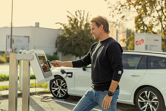 Mann der ein E-Auto lädt